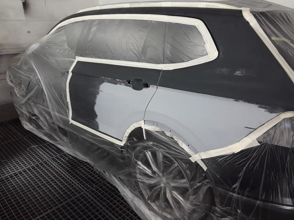 Véhicule masqué et recouvert d’apprêt dans la cabine de peinture de l’atelier