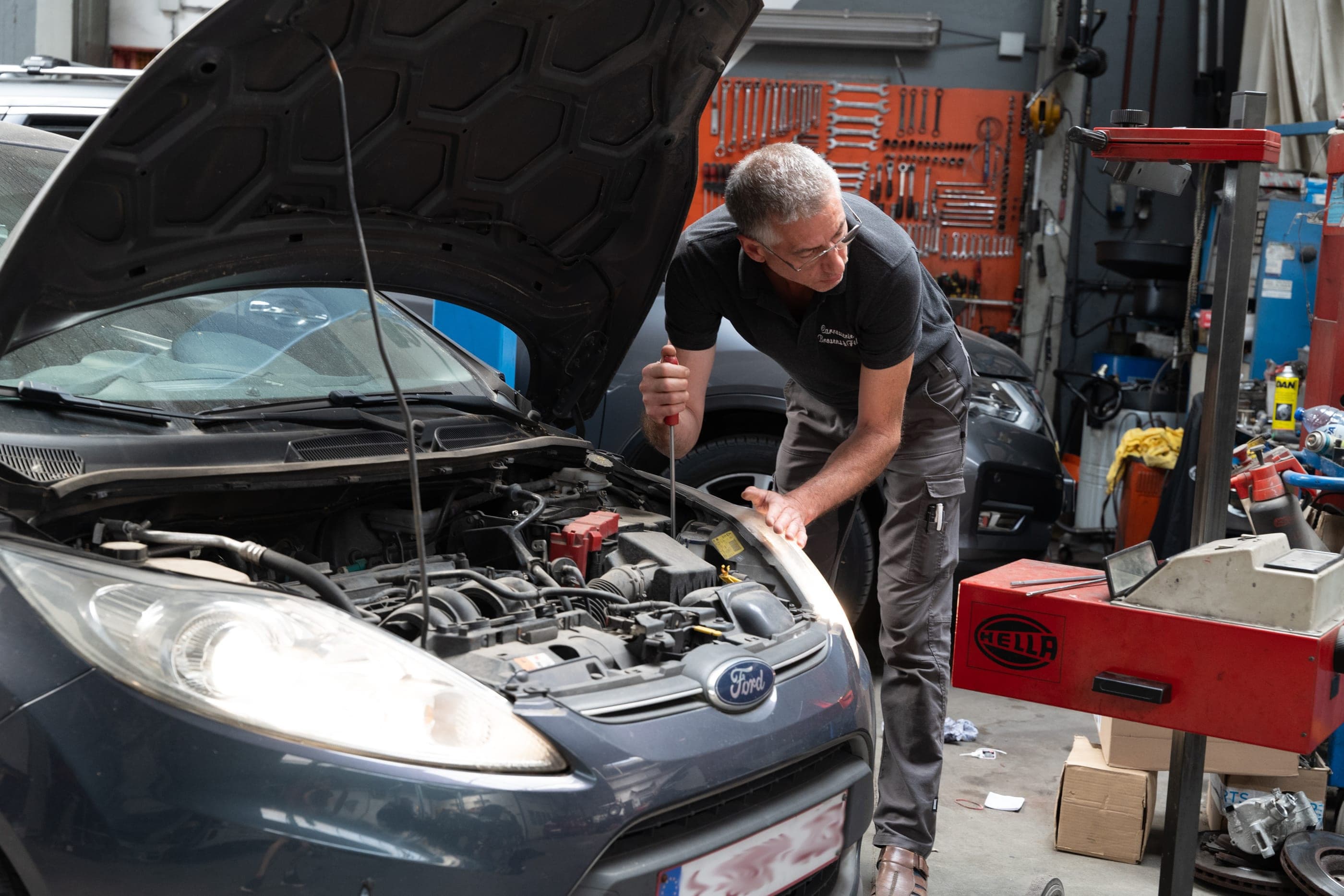 Alain Brosens inspecte le compartiment moteur d’une voiture avant son passage au contrôle technique